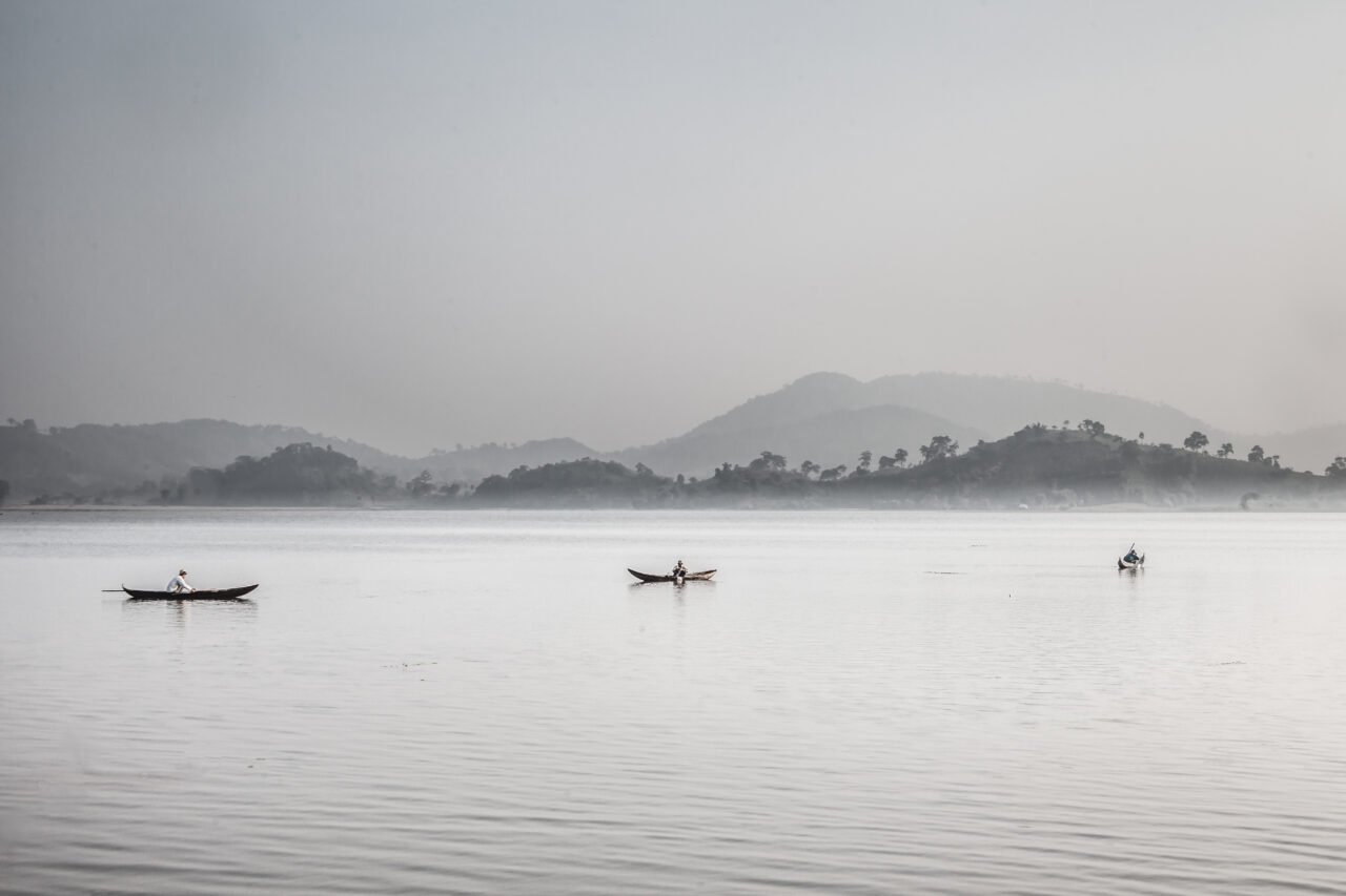 Three fishermen on boat during mist sunrise at Lak Lake
